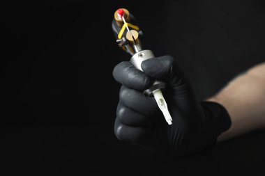 Siyah arkaplanda profesyonel makineli dövme sanatçısı, yakın plan