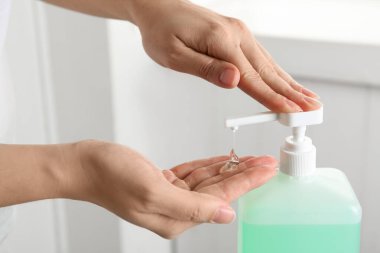Kapalı mekanda antiseptik jel kullanan bir kadın.