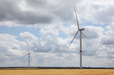 Bulutlu bir günde modern rüzgar türbinleri tarlada. Alternatif enerji kaynağı