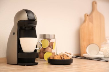 Mutfaktaki ahşap tezgahta modern kahve makinesi.