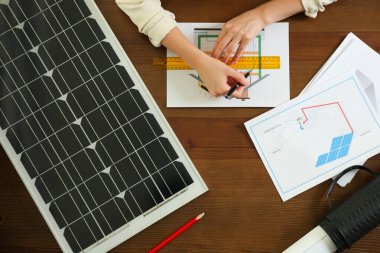 Ahşap masadaki güneş panelleriyle ev projesinde çalışan mimar. Alternatif enerji kaynağı