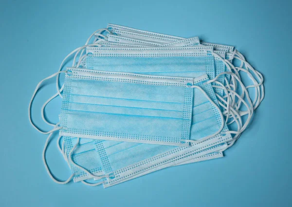 Disposable face masks on light blue background, flat lay. Protective measures during coronavirus quarantine