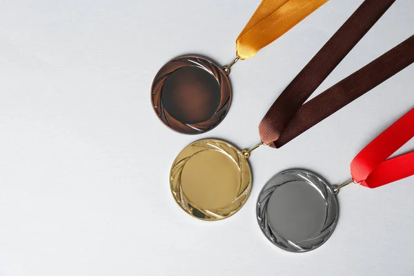 Gold, silver and bronze medals on white background, flat lay. Space for design