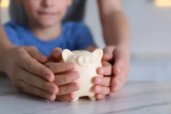 Moeder Zoon Met Spaarvarken Bank Aan Marmeren Tafel Binnen Close — Stockfoto