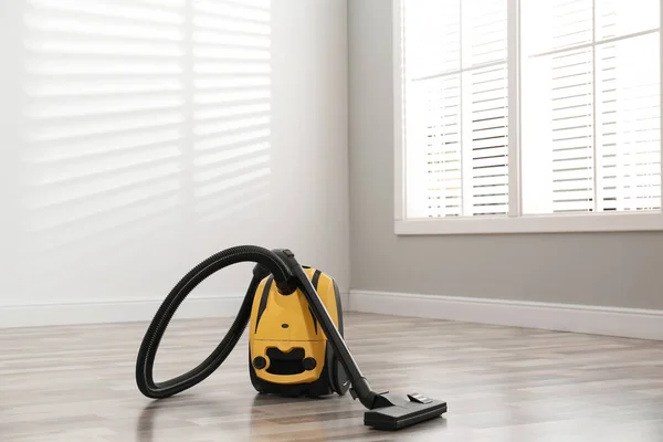 Modern yellow vacuum cleaner on floor indoors