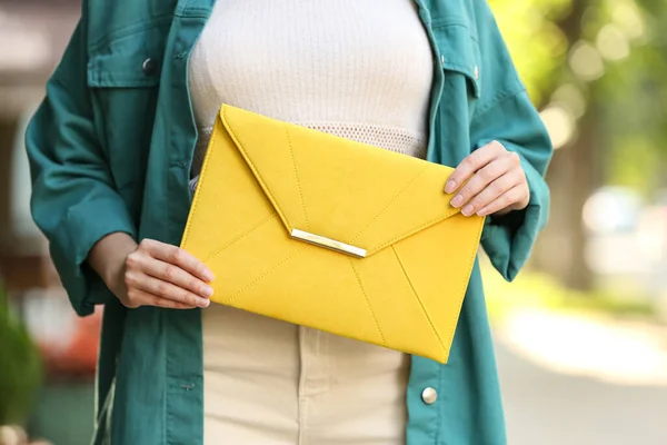 Young woman with elegant envelope bag outdoors on summer day, closeup
