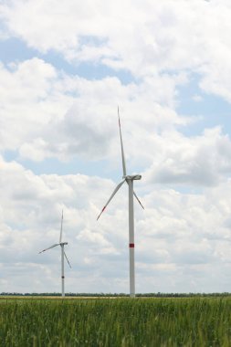 Bulutlu bir günde modern rüzgar türbinleri tarlada. Alternatif enerji kaynağı