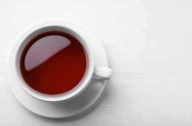 Beyaz ahşap masada bir fincan lezzetli siyah çay, üst manzara. Metin için boşluk