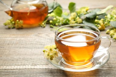 Tahta masada bir fincan çay ve ıhlamur çiçeği. Metin için boşluk