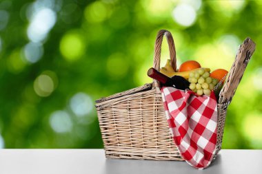 Şaraplı hasır piknik sepeti ve açık havada farklı meyveler, mesaj için yer.