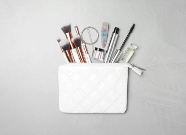 Makyaj ürünleri ve açık gri arka planda güzellik aksesuarları olan kozmetik çanta.