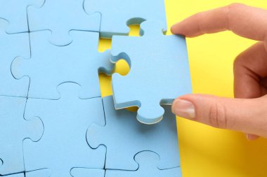 Sarı arka plana açık mavi yapboz parçası koyan kadın, yakın plan. Kariyer tanıtımı konsepti