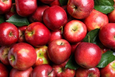 Pile of tasty red apples with leaves as background, top view clipart