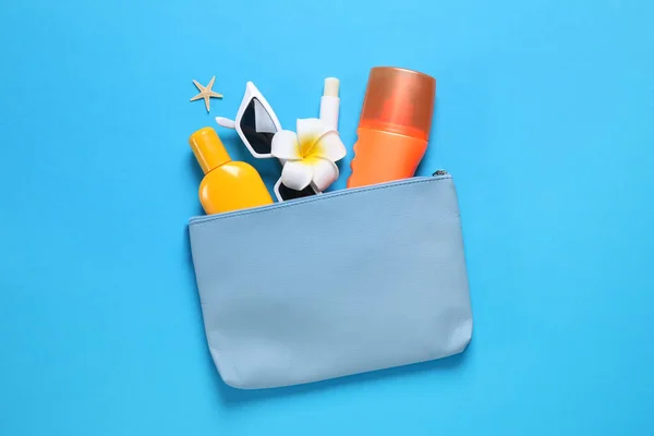 Sun protection products and sunglasses in bag on blue background
