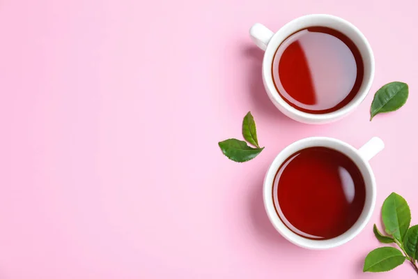 Kubki Aromatycznej Czarnej Herbaty Zielonych Liści Różowym Tle Płaskie Leżaki — Zdjęcie stockowe