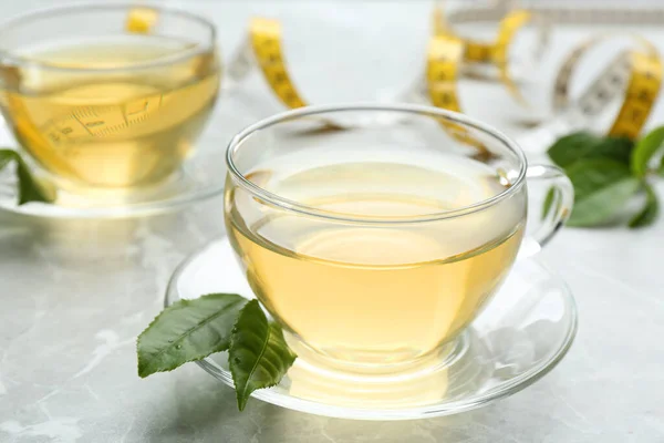 Herbal diet tea and measuring tape on light table