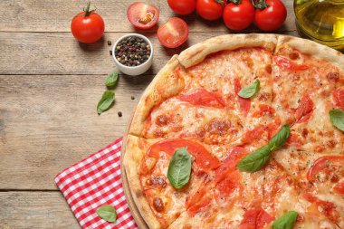 Lezzetli pizza Margherita ve ahşap masa üzerindeki malzemeler.