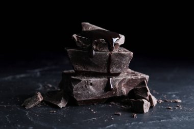 Lezzetli siyah çikolata parçaları siyah masa üzerinde şurup, yakın plan.