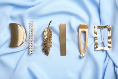 Açık mavi kumaş üzerinde şık saç tokaları, düz yatış.