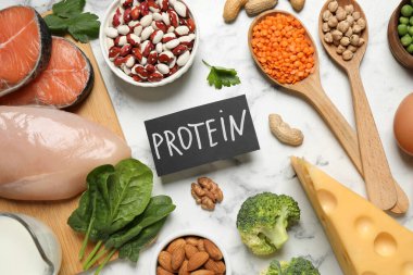Kelime PROTEIN ve beyaz mermer tablo üzerinde farklı ürünler içeren kart, düz yatıyordu