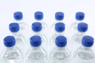 Beyaz arka planda saf su bulunan plastik şişeler, yakın plan.