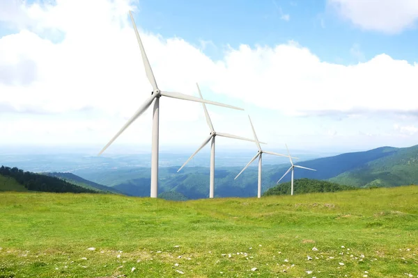 Alternative energy source. Wind turbines in mountains under cloudy sky