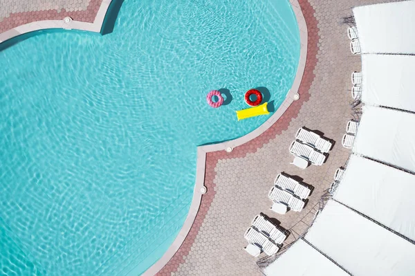 Inflatable rings and mattress floating in swimming pool, top view. Summer vacation