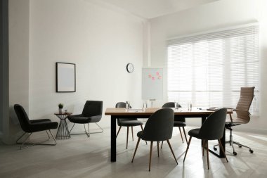 Büyük masası ve sandalyeleri olan basit bir ofis.