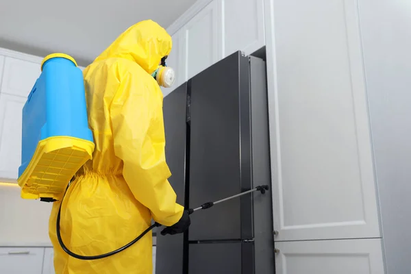 冷蔵庫の近くに殺虫剤を噴霧保護スーツの害虫駆除の労働者屋内 — ストック写真