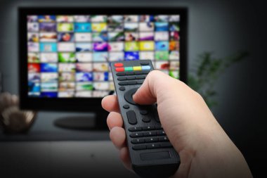 Yayınlanan video servisleri. TV 'de kanal değiştirmek için uzaktan kumanda kullanan kadın, kapat