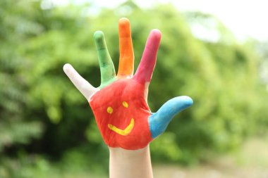 Yeşil parktaki avuç içine gülümseyen yüzü olan çocuk, yakın plan.