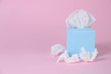 Kağıt mendilli kutu ve pembe arka planda buruşmuş peçeteler, metin için boşluk