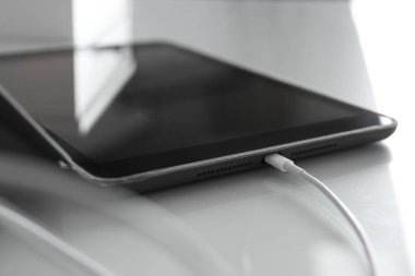 Tablet beyaz masada şarj ediliyor, görüntüyü kapat
