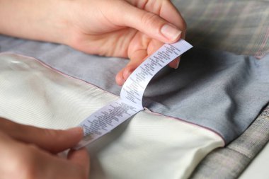 Hafif giysi hakkında içerik bilgisiyle etiketi okuyan kadın, yakın plan