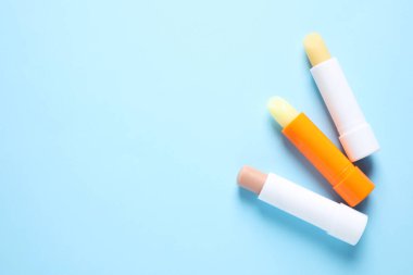 Açık mavi arka planda hijyenik rujlar, düz yatış. Metin için boşluk