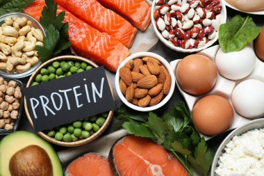 Kelime PROTEIN ve arkaplan olarak farklı ürünler içeren kart, düz yatıyordu