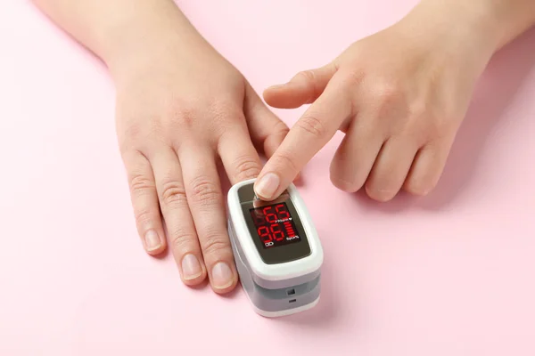 ピンクの背景に指先パルス酸素濃度計を使用している女性 クローズアップ — ストック写真