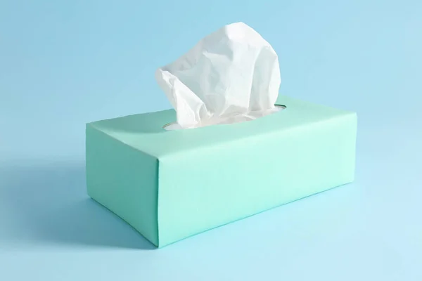 Box of paper tissues on light blue background