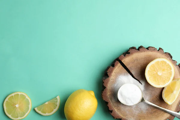 Baking soda and lemons on turquoise background, flat lay. Space for text