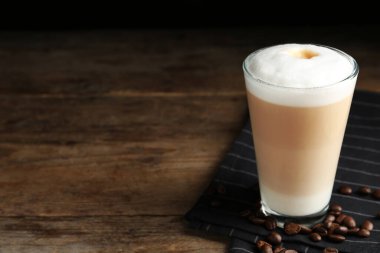 Lezzetli latte macchiato ve kahve çekirdekleri ahşap masada. Metin için boşluk