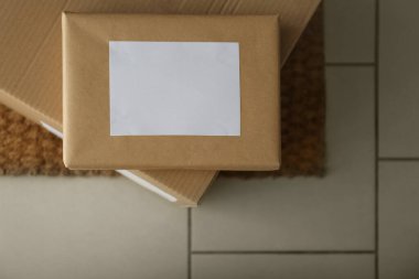 Kapı girişinin yanındaki kilimde paketler var. Teslimat servisi