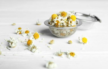 Kuru papatya çiçekleri beyaz ahşap masada, yakın plan.