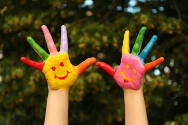 Yeşil parktaki avuç içlerine gülümseyen çocuk, yakın plan.