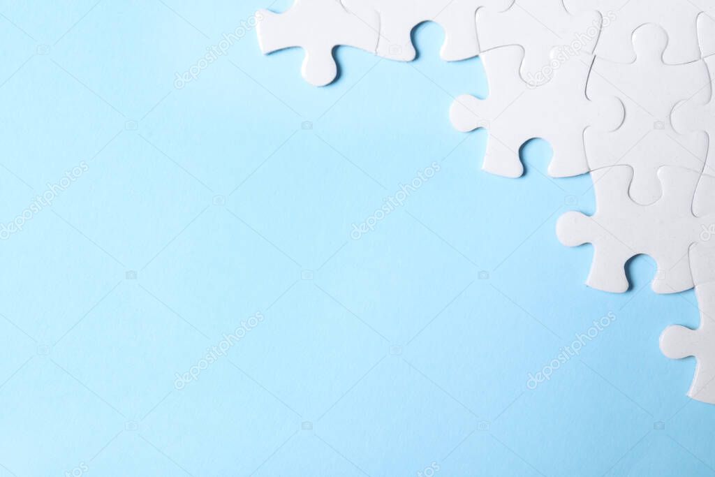 Blank white puzzle pieces on light blue background, flat lay. Space for text