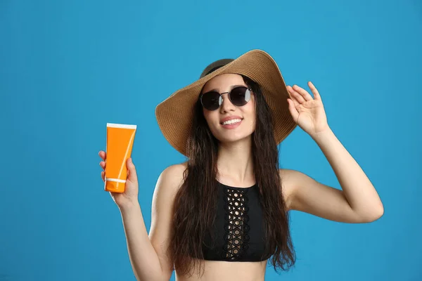 Junge Frau Mit Sonnenschutzcreme Auf Blauem Hintergrund — Stockfoto