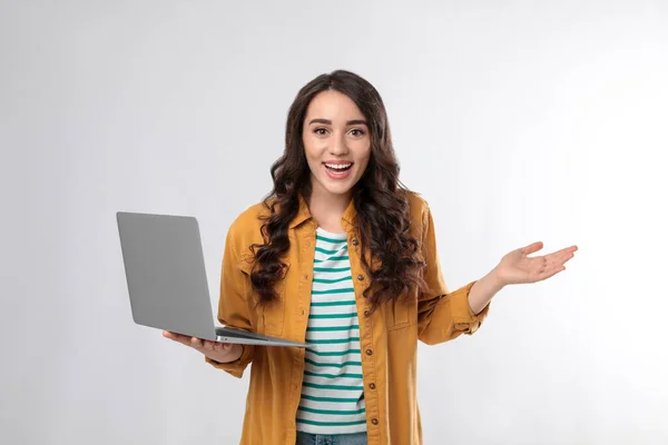 Surprised young woman with laptop on white background