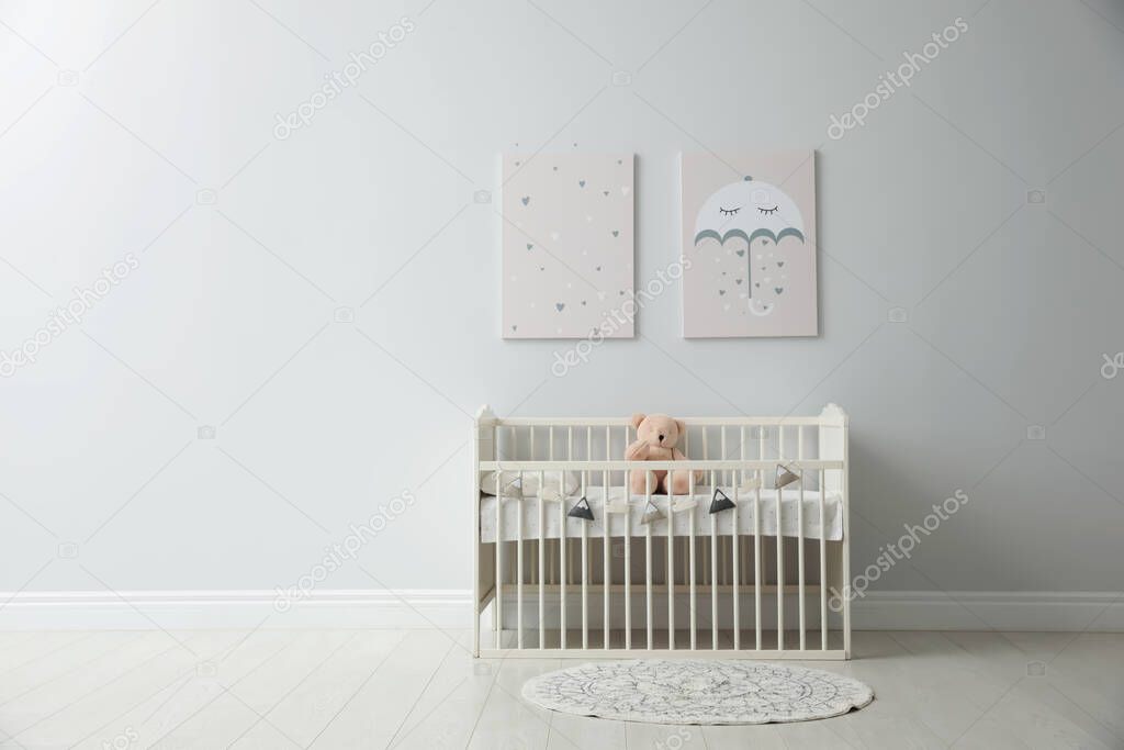 Minimalist room interior with baby crib, decor elements and toys. Space for text