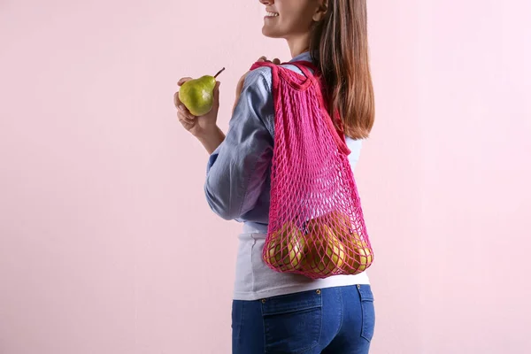 ピンクの背景に新鮮な熟した梨と女性がネットバッグを保持 クローズアップ — ストック写真