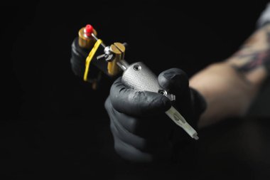 Masada siyah arkaplana karşı profesyonel makineli dövme sanatçısı, yakın plan