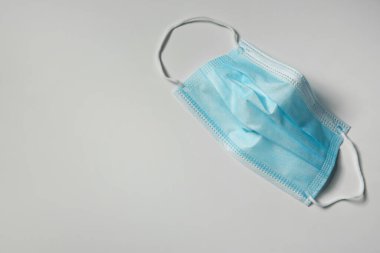 Işık arkaplanındaki tek kullanımlık yüz maskesi, metin için boşluk olan üst görünüm. Koronavirüs karantinası sırasında koruyucu tedbirler